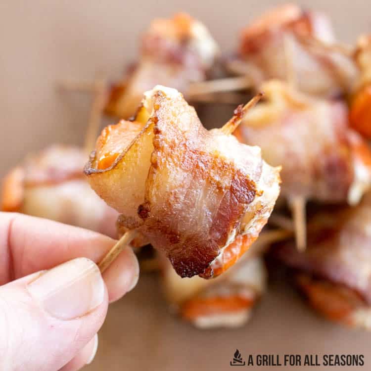 hand holding a bacon wrapped salmon bite