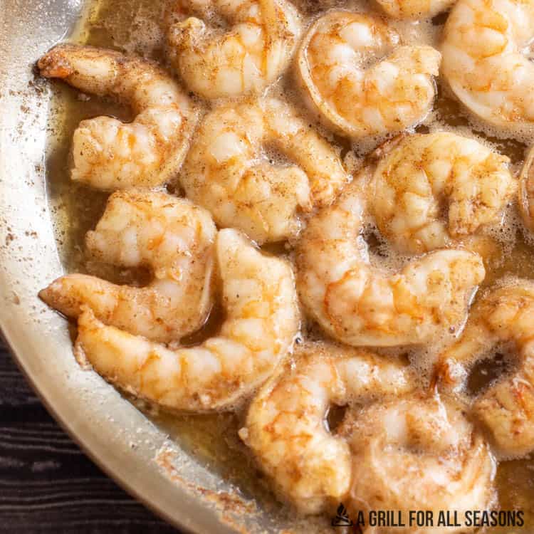 shrimp poached in butter in pan close up