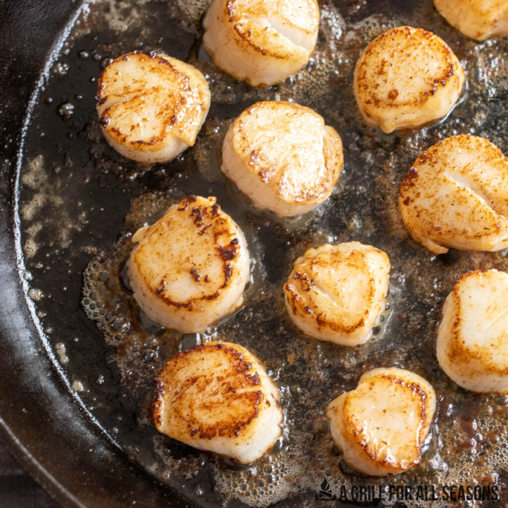scallops cooking in butter in a cast iron pan