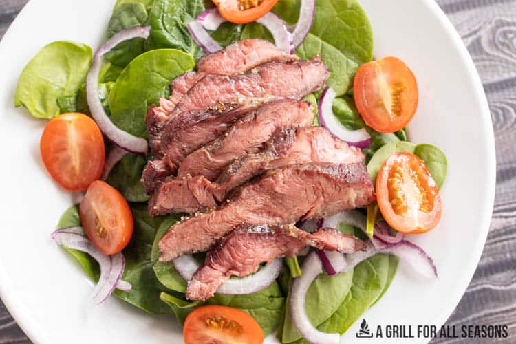 salad topped with smoked flat iron steak from overhead