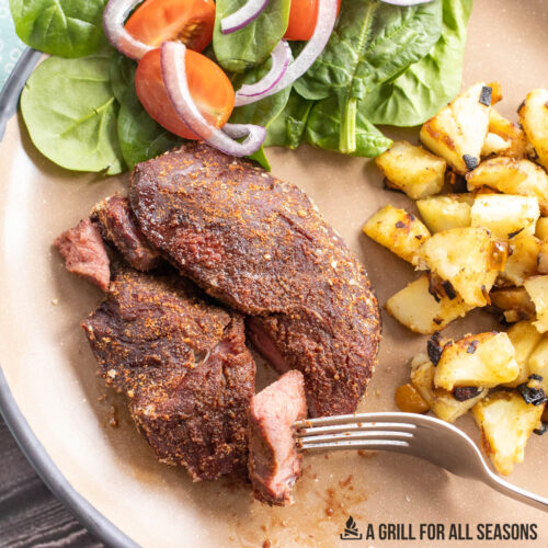 smoked venison steak plated with salad and potato mash