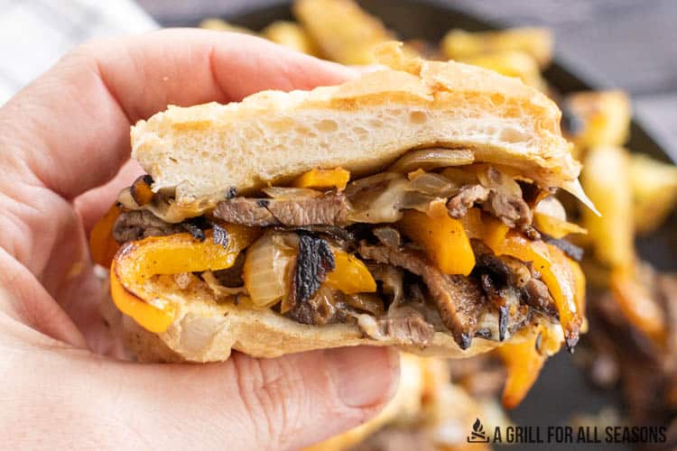 venison philly cheesesteak half being held in a hand