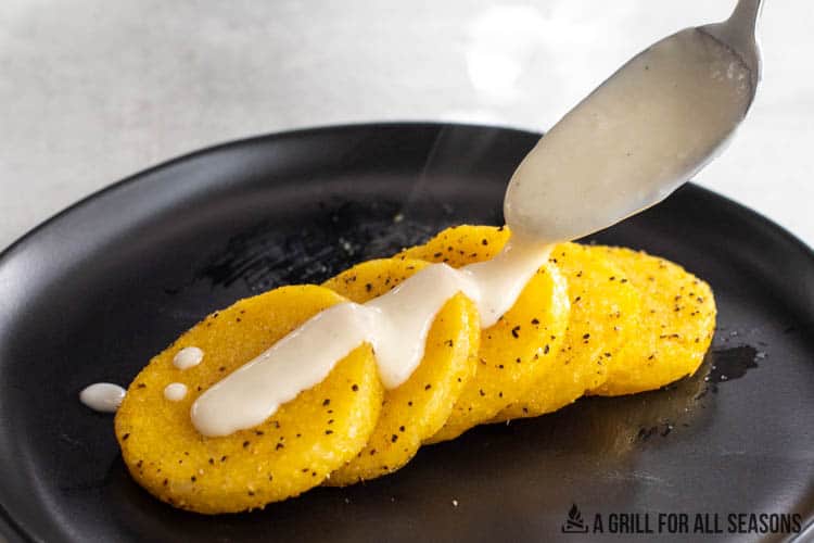 polenta on plate with bechamel being drizzled on top