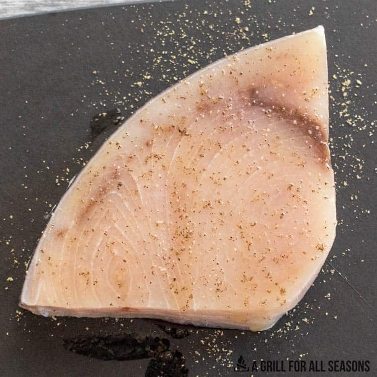 raw fish with seasoning on cutting board