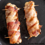 grilled alligator wrapped in bacon on cutting board
