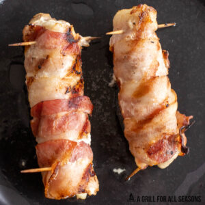 grilled alligator wrapped in bacon on cutting board