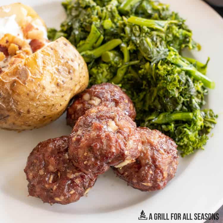 smoked elk meatballs on plate with baked potato and broccoli rabe