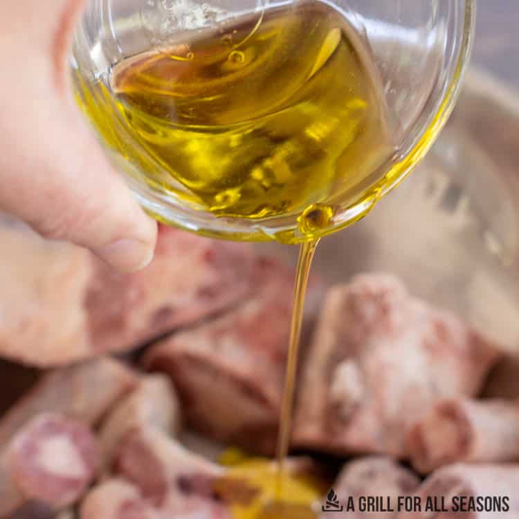 hand pouring oil over the meat