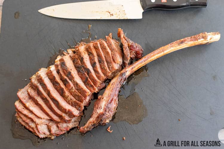 smoked tomahawk steak sliced on cutting board