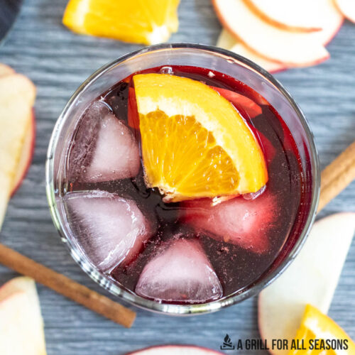 glass of bourbon sangria on ice with orange slice garnish