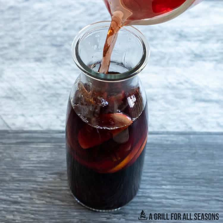 pouring cranberry juice into sangria pitcher