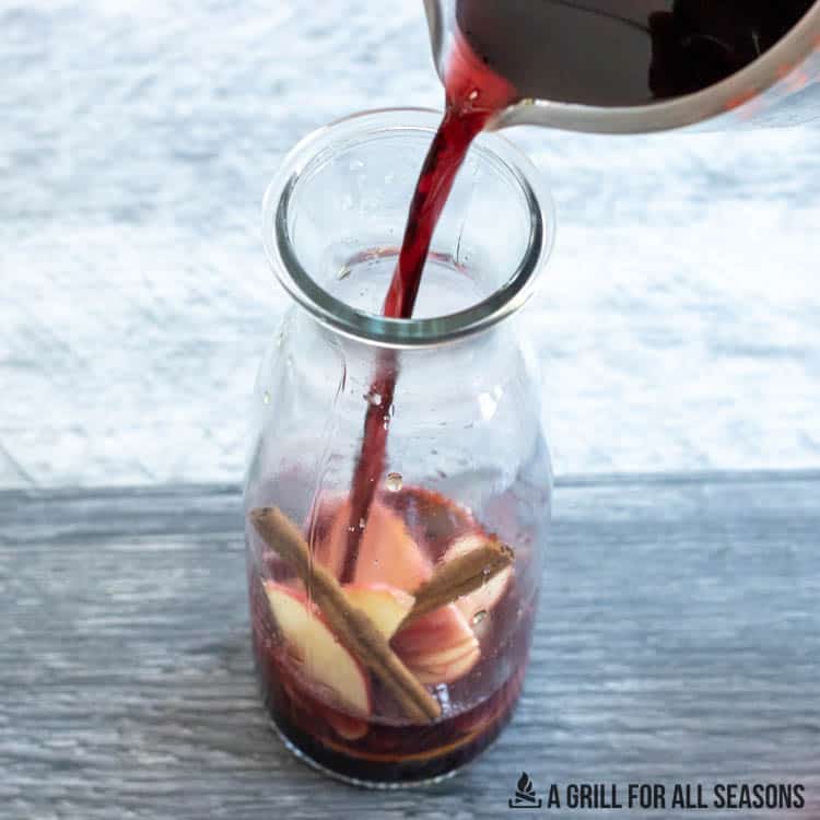 red wine being added to fruit in sangria pitcher