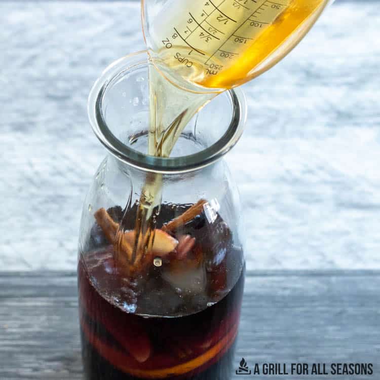 bourbon being added to ingredient in sangria pitcher