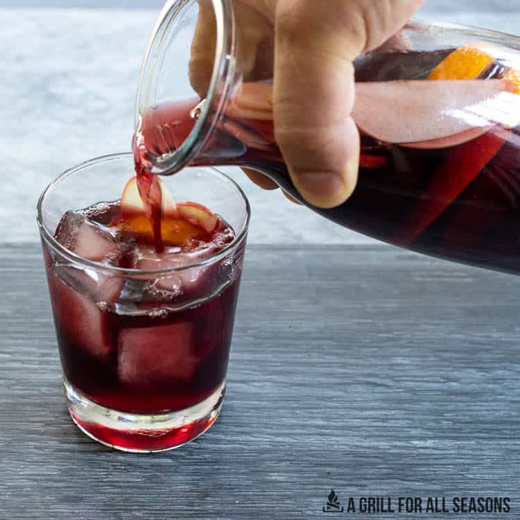 pouring bourbon sangria into a glass with ice