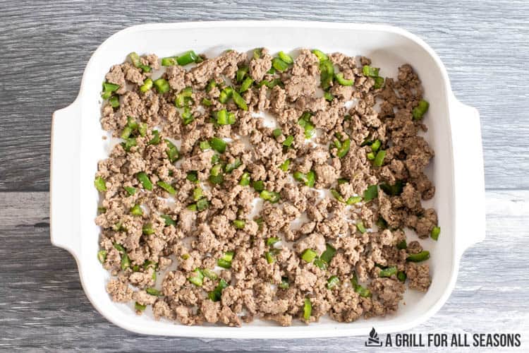 casserole dish with browned beef and cooked green peppers