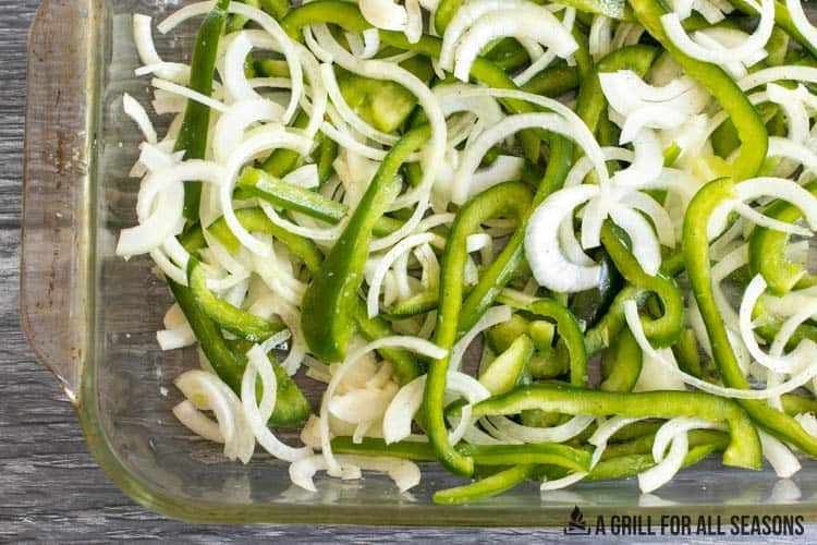 sliced peppers and onions in casserole dish