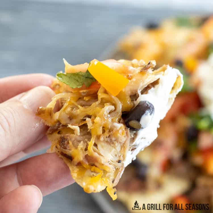 hand holding chip with nacho toppings