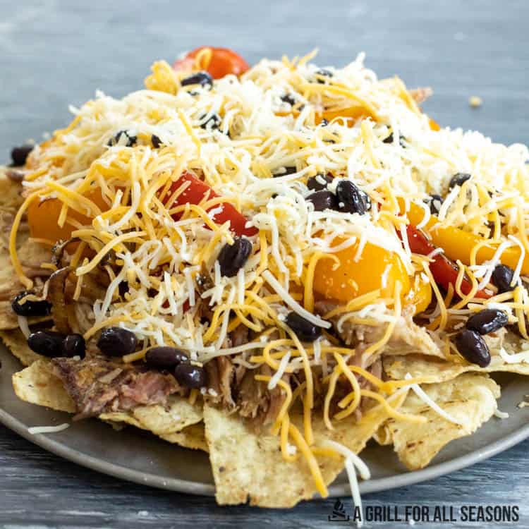 nachos covered with pulled pork, cheese, and other toppings