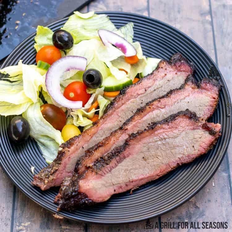 slices of brisket on plate with salad