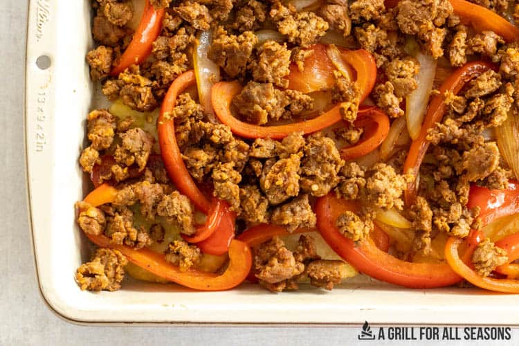 chorizo, peppers, and onions in pan on top of hashbrowns
