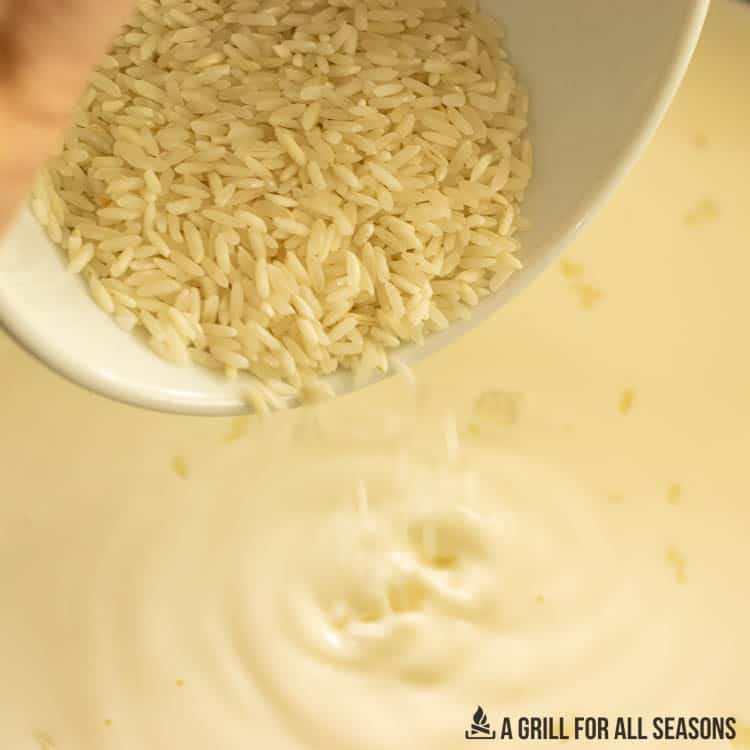 raw rice being added to pot of milk