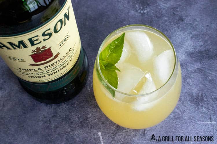 irish lemonade in glass with basil garnish. Bottle of jameson