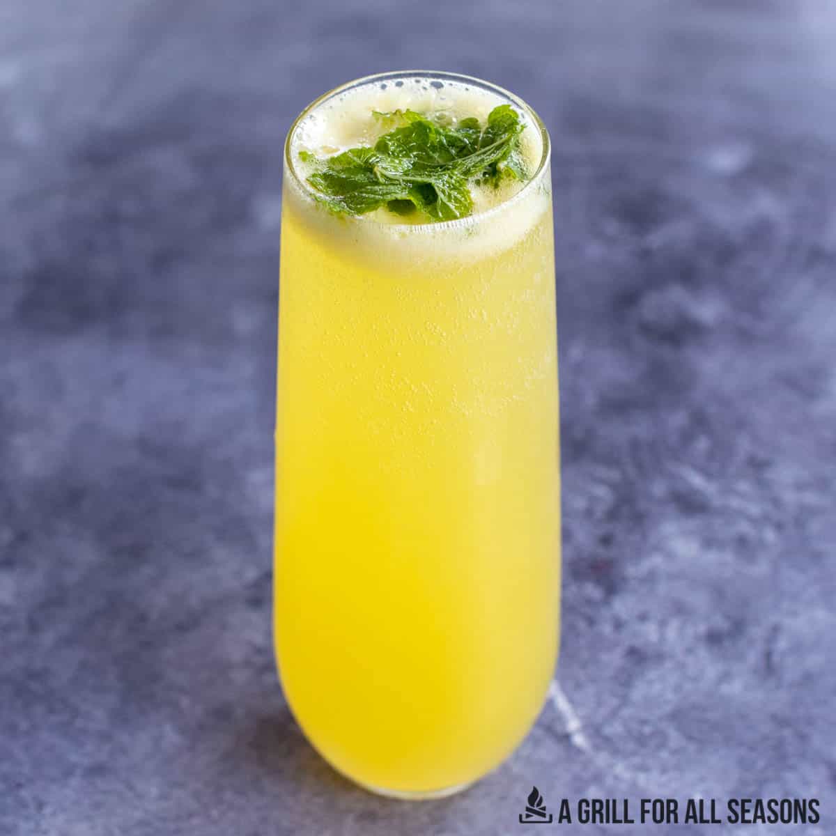 tropical mojito recipe with passion fruit juice served in a stemless champagne glass with mint