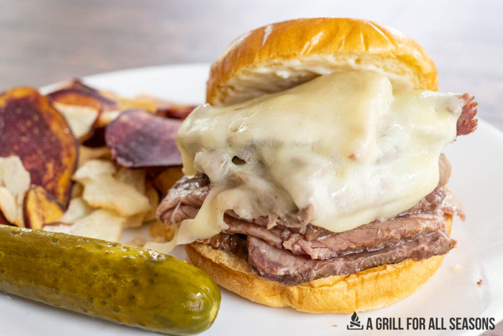 smoked bottom round roast beef sandwich on brioche with provolone, chips, and a pickle.