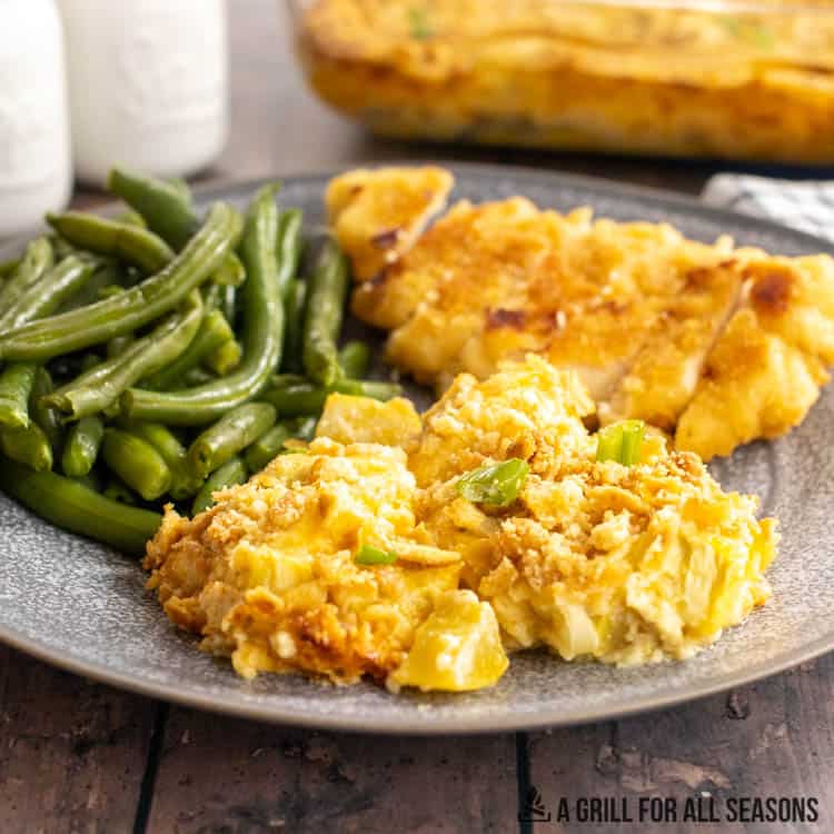 squash casserole on a plate with green beans and chicken