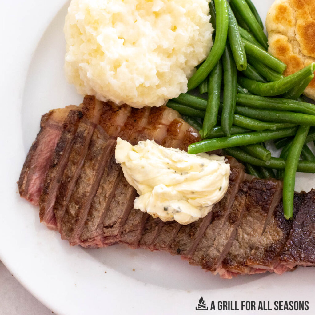 steak plated with green beans and mashed potatoes