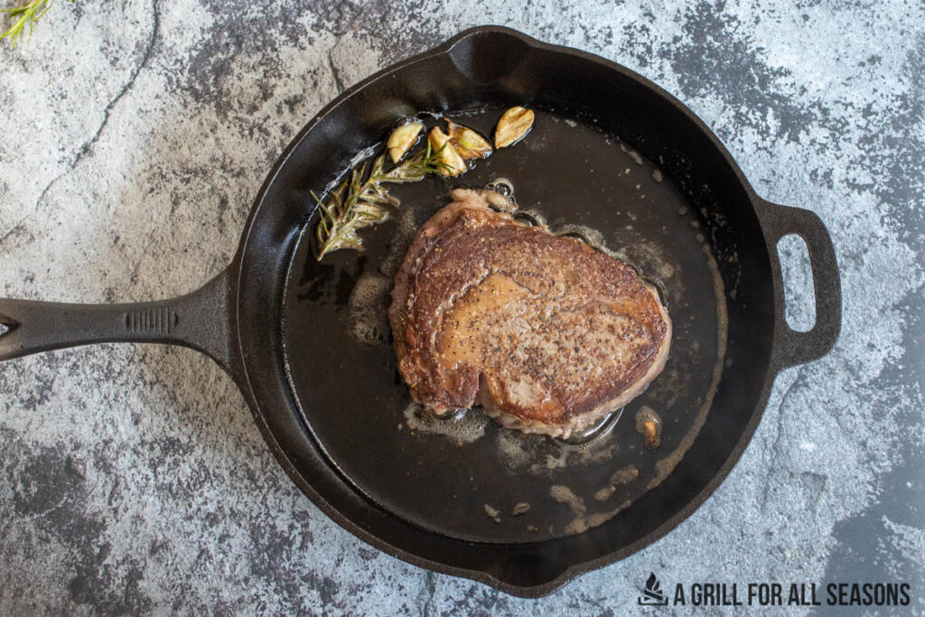 steak cooking in cast iron skillet