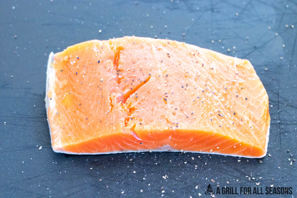 salmon filet seasoned on cutting board
