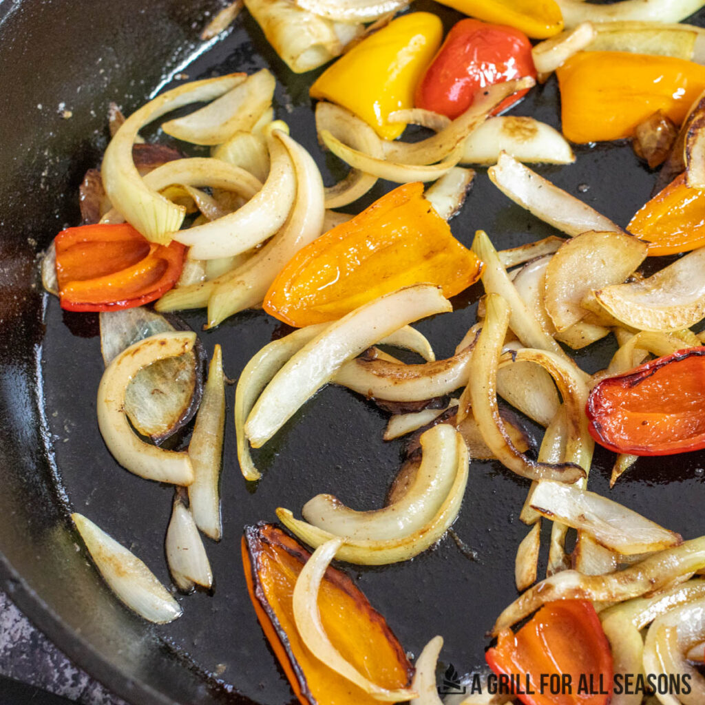 onions and peppers sauteeing in a skillet