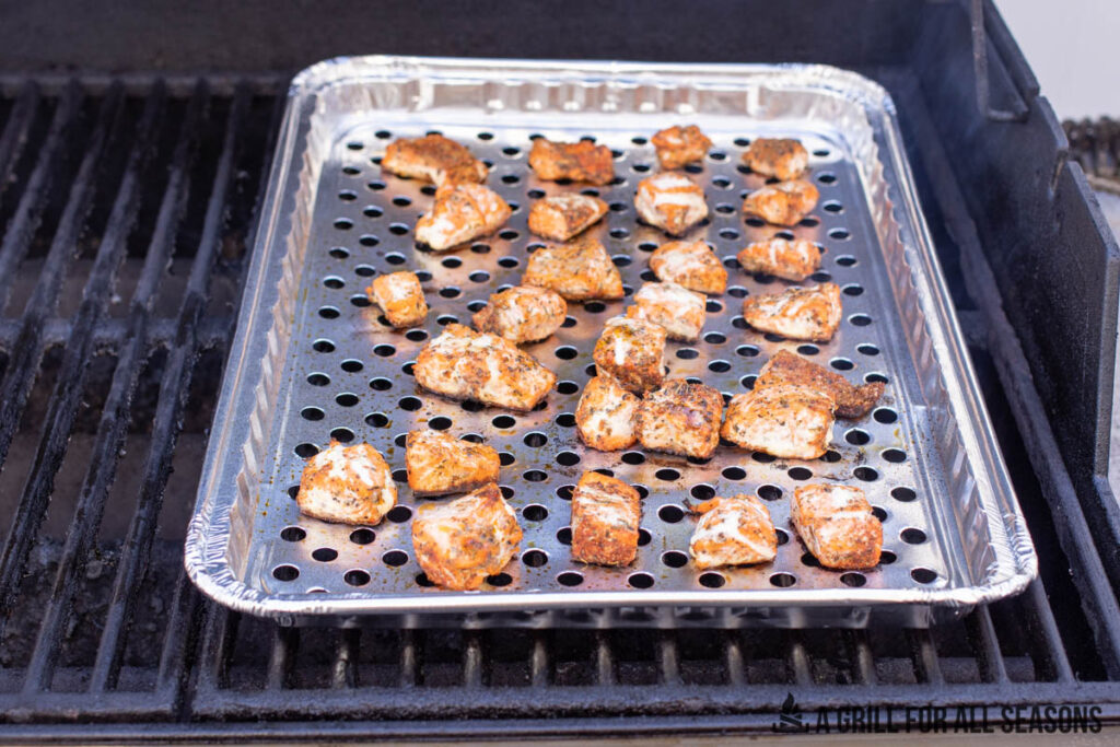 small chunks of fish in aluminum grill pan on grill