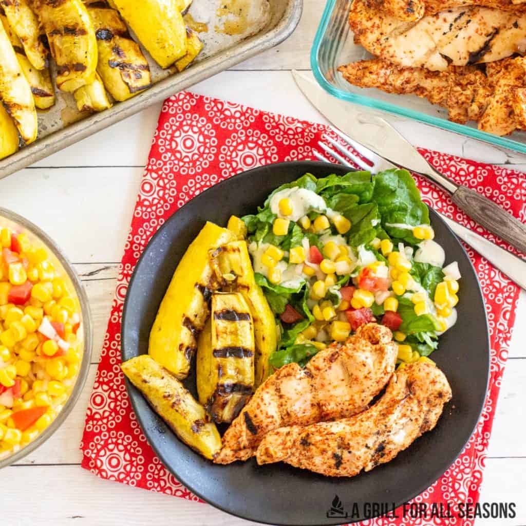 dinner spread with tajin chicken, grilled squash, and corn salad