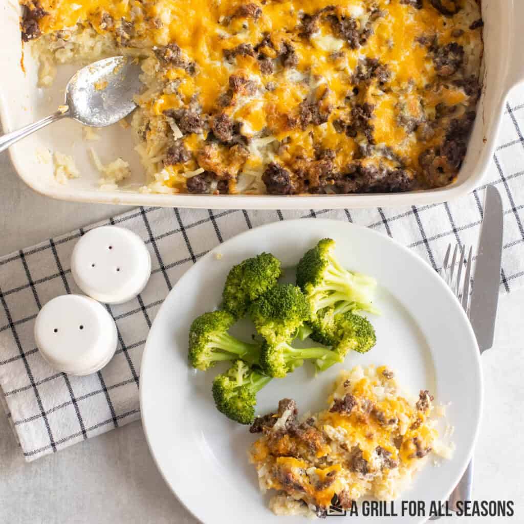 ground beef hashbrown casserole on dinner plate with baking dish from overhead