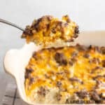 ground beef hashbrown casserole recipe being served from baking dish with spoon
