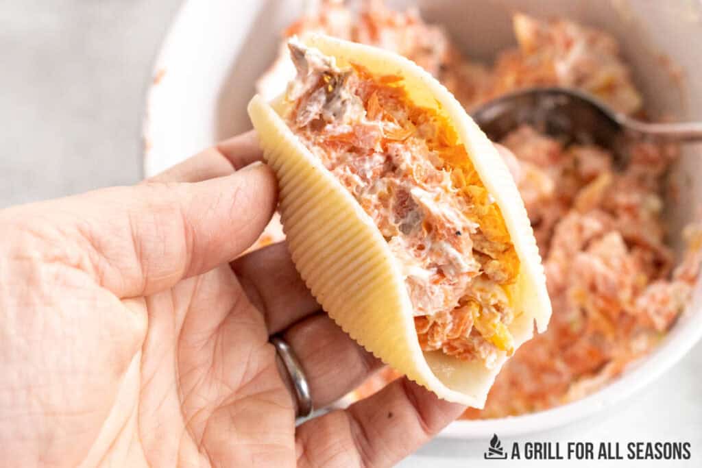 hand holding up a pasta shell with filling