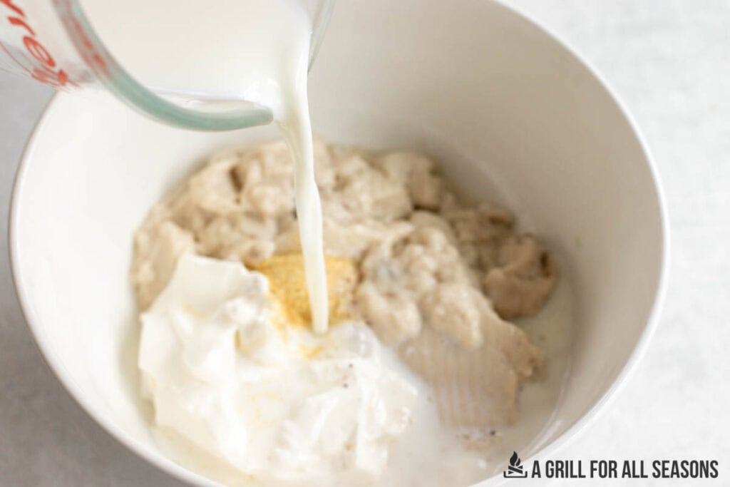 milk being added to sauce in bowl