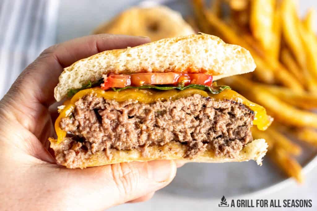 hand holding up a halved cowboy butter burger