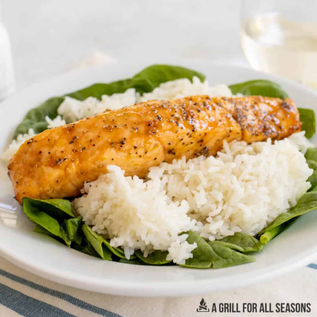 close up of a hot honey salmon filet with rice and spinach