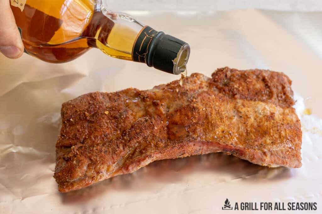 hand pouring some bourbon over the meat