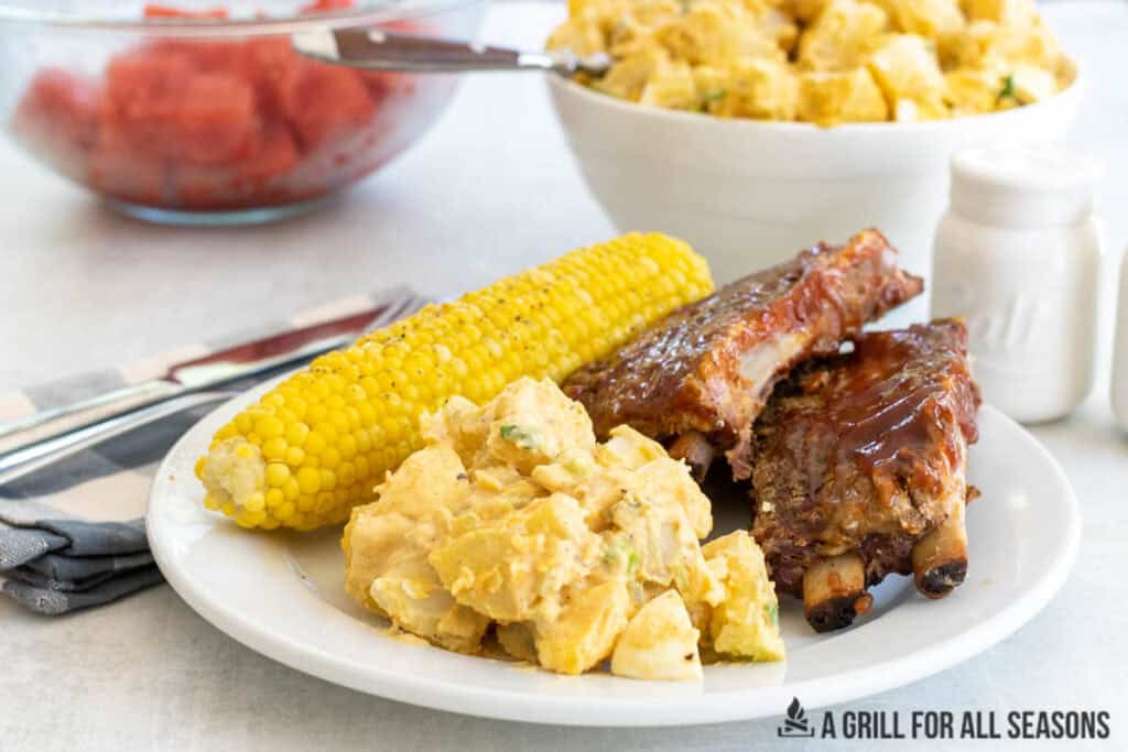 southern potato salad on plate with bbq ribs and corn on the cob