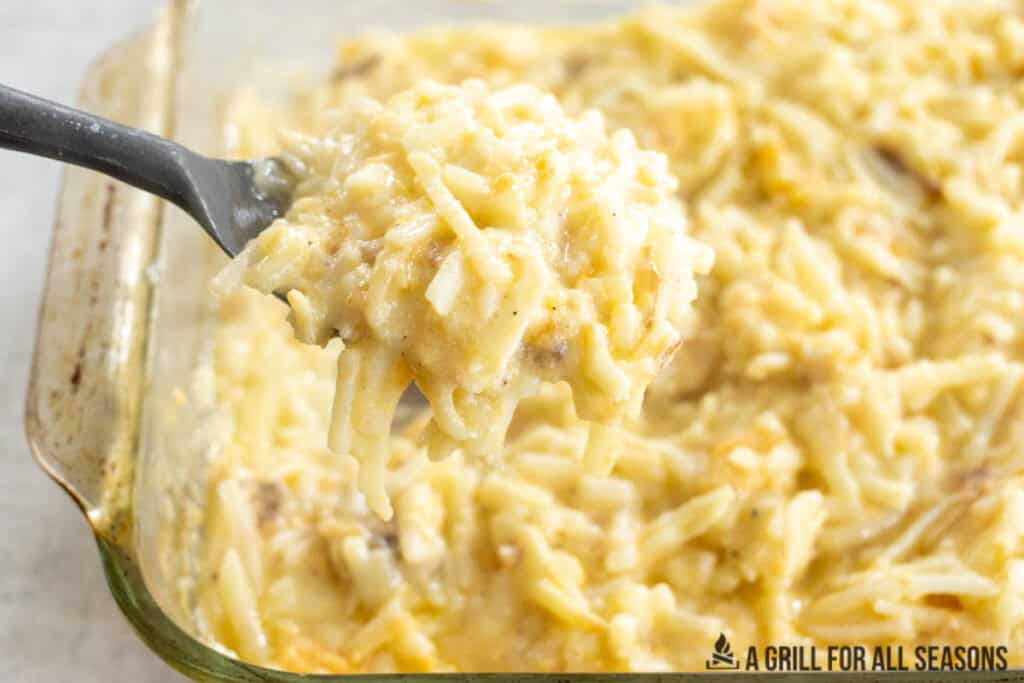 serving spoon lifting up some of the cheesy breakfast potatoes