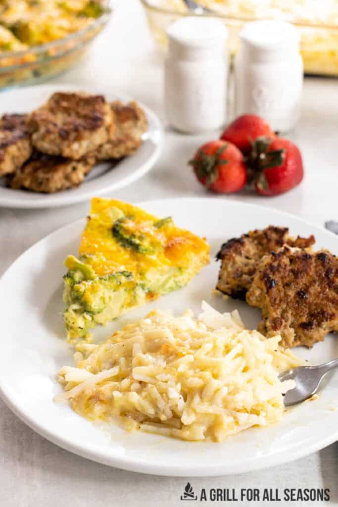 cheesy breakfast potatoes served on a plate with quiche and sausage