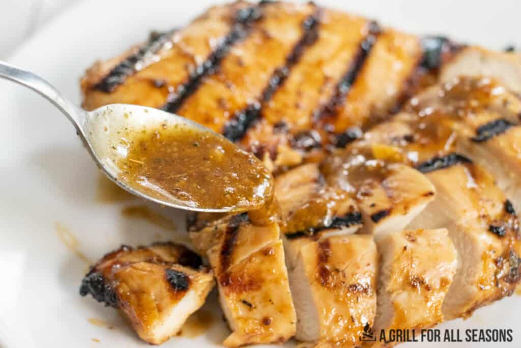spoon drizzling sauce on the chicken
