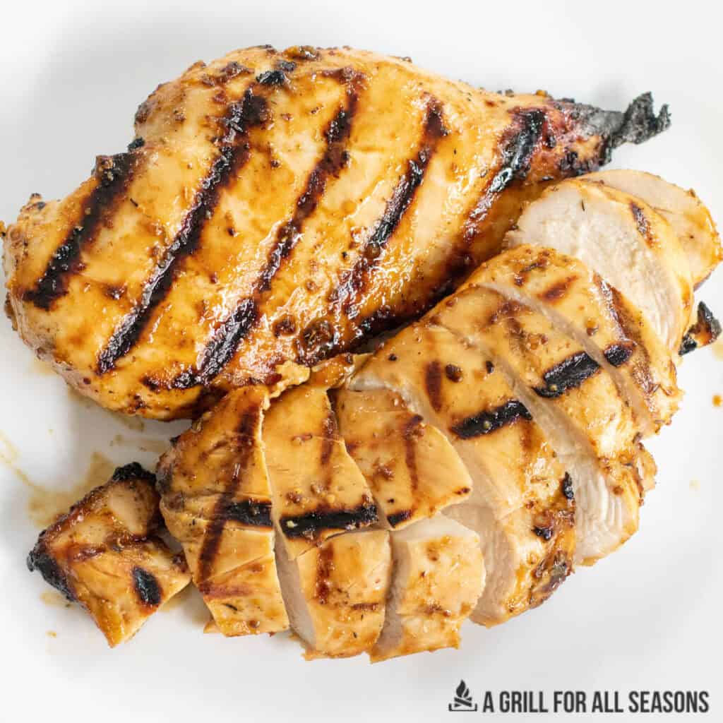 honey mustard grilled chicken breasts shown whole and sliced on a dinner plate
