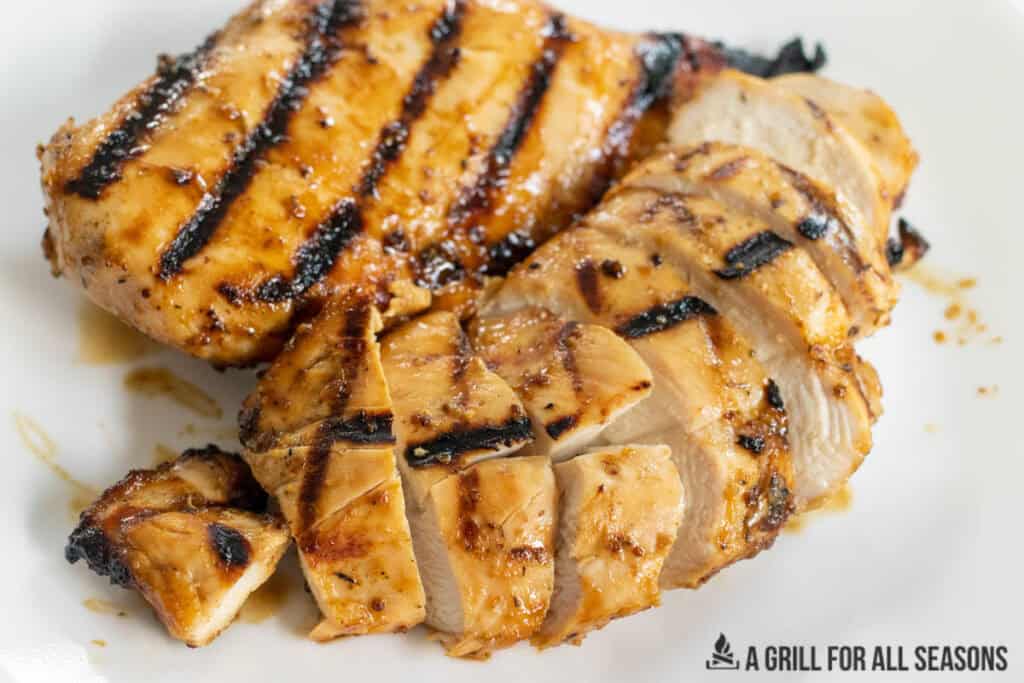 honey mustard grilled chicken breasts shown whole and sliced on a dinner plate