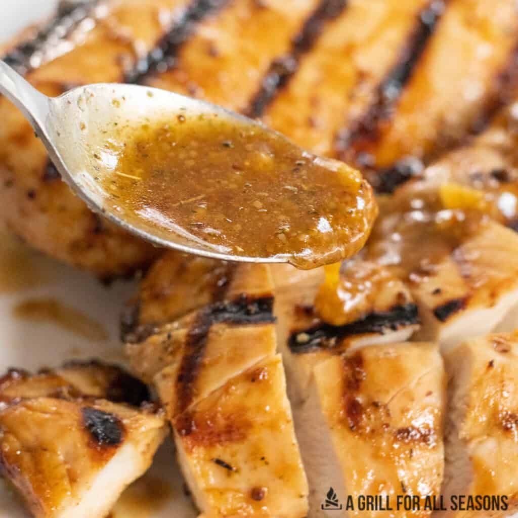 reserved marinade being drizzled over sliced chicken