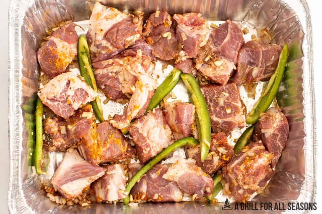 pork in pan with seasonings and peppers